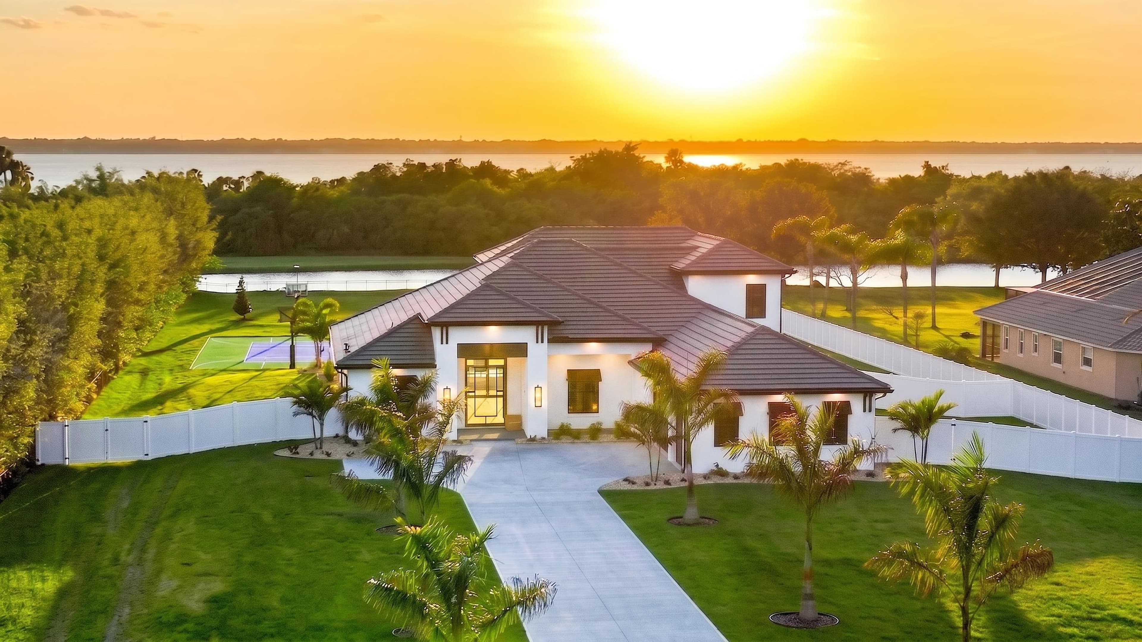Drone aerial of a lakefront PMH listing at sunset, water on the horizon